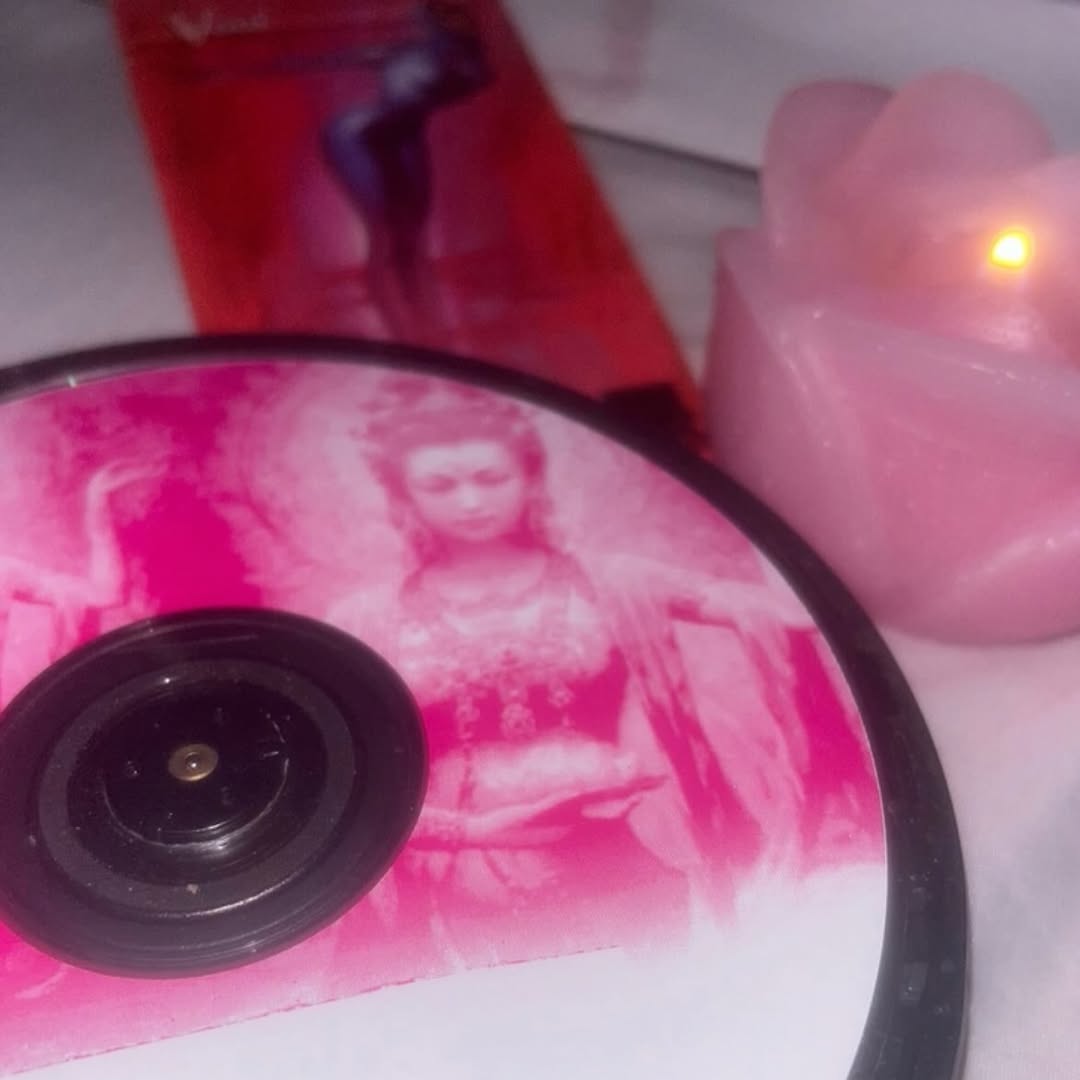 Detalle de un disco con imagen rosa junto a una vela.