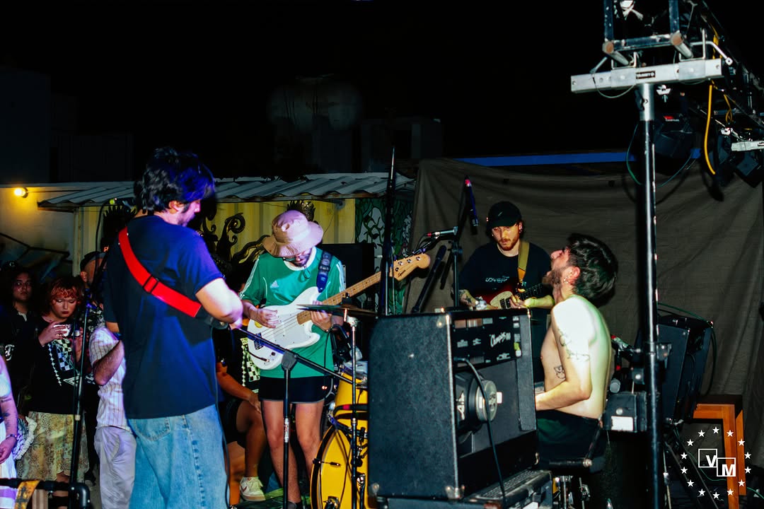 Músicos con guitarras y batería en el evento compartido por Dolorio y Los Tunantes y Asia Menor; público junto al escenario.